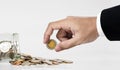 Hand picking up coin from spilled from glass jar