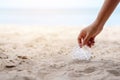 A hand picking up a plastic glass trash on the beach Royalty Free Stock Photo