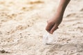 A hand picking up a plastic glass trash on the beach Royalty Free Stock Photo