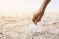 A hand picking up a plastic glass trash on the beach Royalty Free Stock Photo