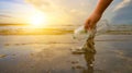 The hand is picking up trash on the beach, the idea of environmental conservation Royalty Free Stock Photo