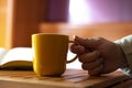 Hand picking up a yellow cup of coffee at home Royalty Free Stock Photo
