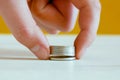 Hand picks up a stack of coins close-up lying on a white table.