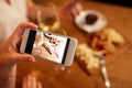 Hand picturing food by smartphone at wine bar