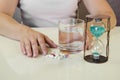 Hand with pill, water and glass of water