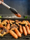Hand with pincer placing a sausage on the grill Royalty Free Stock Photo