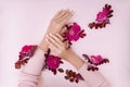 Hand with pink flowers and petals lying on a paper background. Cosmetics for hand skin care. Natural petal cosmetics, essential