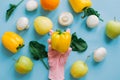 Hand in pink glove picking bell pepper on blue background with vegetables flat lay. Safe shopping in quarantine. Order food online