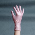 Hand in pink nitrile glove on a gray background with a gradient