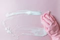 Hand in a pink rubber glove holds a cleaning sponge and wipes a soapy foam on a pink background. Royalty Free Stock Photo