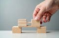Hand places final wooden block toy bridge. Connecting, joining problem solution. Concept of teamwork, collaboration, business, Royalty Free Stock Photo