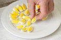 Hand places quartered quail eggs on a plate for breakfast, brunch or party buffet, selected focus