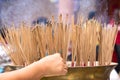 Hand places a stick of incense at a large pot