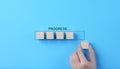 Hand places wooden cubes arranged in row on blue background. with the word progress. in progress, work loading bar, achievement Royalty Free Stock Photo