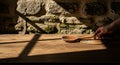 A hand places a wooden spoon on a rustic wooden table. The scene is lit by natural light, casting Royalty Free Stock Photo