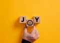 Hand places the word joy on wooden blocks with a smiling face symbol. Joy, happiness, pleasure, joyful emotion Royalty Free Stock Photo