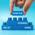 Hand placing a blue block labeled Future Plan on of a blue block structure with Skill Set, Networking Royalty Free Stock Photo