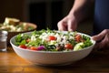 hand placing bowl of greek salad on table Royalty Free Stock Photo