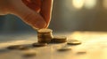 Hand placing coins on a stack in a softly lit room during late afternoon Royalty Free Stock Photo