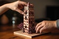 a hand placing the final piece on a wooden block tower