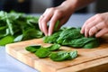 hand placing fresh avocado slices on a bed of spinach leaves