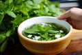hand placing fresh mint leaves on top pho bowl