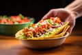 hand placing a hot chalupa into a tortilla bowl