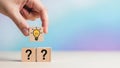Hand Placing Idea Lightbulb Block Over Question Marks on Gradient Background Royalty Free Stock Photo