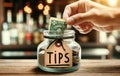 Hand Placing Money into Glass Tip Jar at Restaurant Royalty Free Stock Photo