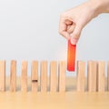 hand placing or pulling Red domino wooden block on table. Business planning, Risk Management, Solution, leader, strategy,