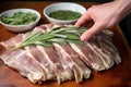 hand placing sage leaves under turkey skin for marinade