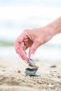 Hand placing Stone on the Pyramid on sand. Sea in the background Royalty Free Stock Photo