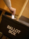 Hand placing vote in ballot box in polling station