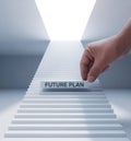 A hand placing a white block labeled future plan on a staircase in a surreal minimal scene Royalty Free Stock Photo