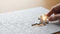 Hand placing final puzzle piece with light bulb. Royalty Free Stock Photo