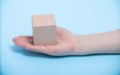 hand placing wooden block on a blue background. A child`s hand holds a cube. Space for your text Royalty Free Stock Photo