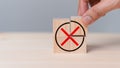 Hand placing wooden cube with red cross checkmark sign. Goals achievement and business success.