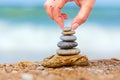 Hand placing the last pebble of a stacked tower