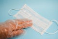 A hand in a plastic glove holds a disposable protective medical mask for protection against dangerous deadly diseases Royalty Free Stock Photo