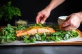 hand plating a fillet of baked salmon with greens