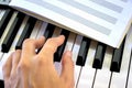 Hand play black and white piano keys a notebook for sheet music lies learning music sheet music playing on the synthesizer