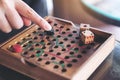 A hand playing wooden Snakes and Ladders game