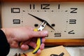 Hand with pliers removing clock hands