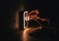 Hand plugging cable into illuminated wall socket in dimly lit room Royalty Free Stock Photo