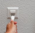 Hand plugging elecric cord into swiss power plug Royalty Free Stock Photo