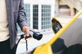 Hand Plugging In Electric Car Outside Office In Car Park Charging