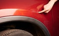 Hand pointing at dent on red car