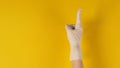 Hand is pointing finger up and wear medical glove on yellow background. Studio shooting Royalty Free Stock Photo
