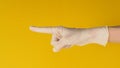 Hand is pointing finger and wear medical glove on yellow background. Studio shooting Royalty Free Stock Photo