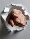 A hand pointing through a hole in a white paper Royalty Free Stock Photo
